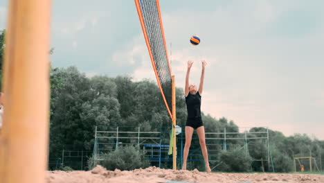 Junge-Frau-Spielt-In-Einer-Mannschaft-Volleyball-Am-Strand-Und-Führt-Einen-Angriff-Durch,-Indem-Sie-Den-Ball-Schlägt.-Mädchen-Schlägt-In-Zeitlupe-Den-Ball-Und-Führt-Einen-Angriff-Durch-Das-Netz-Aus.